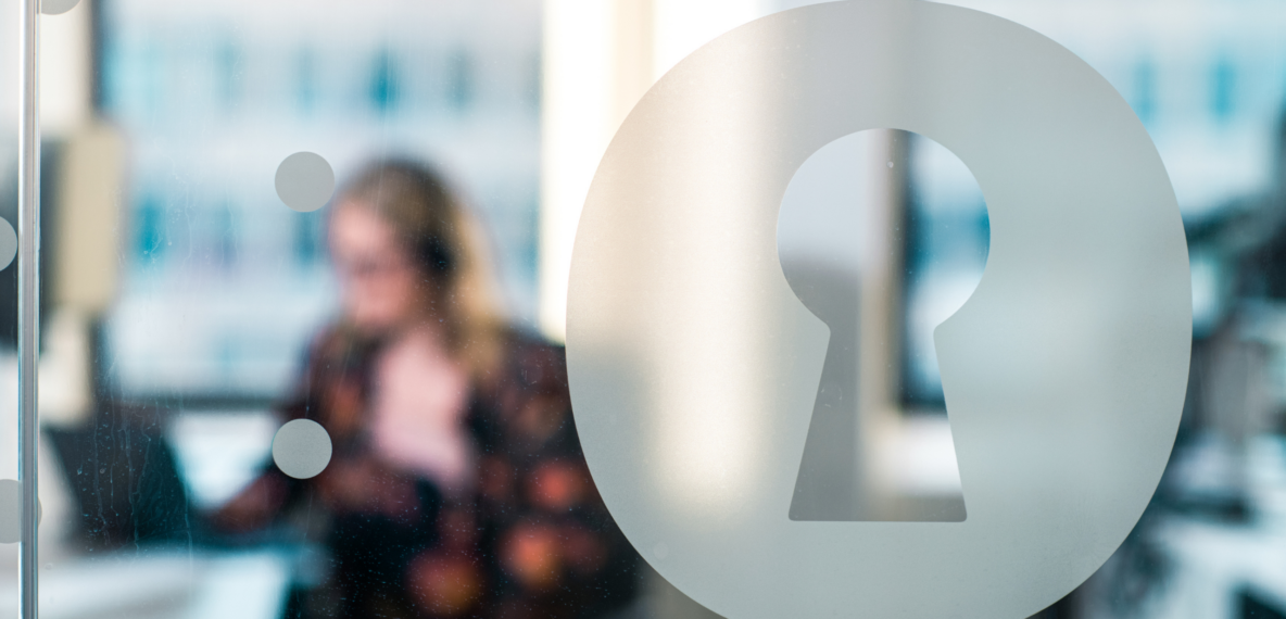 Blurred photo of person sat at office desk behind glass with Homeprotect logo on it